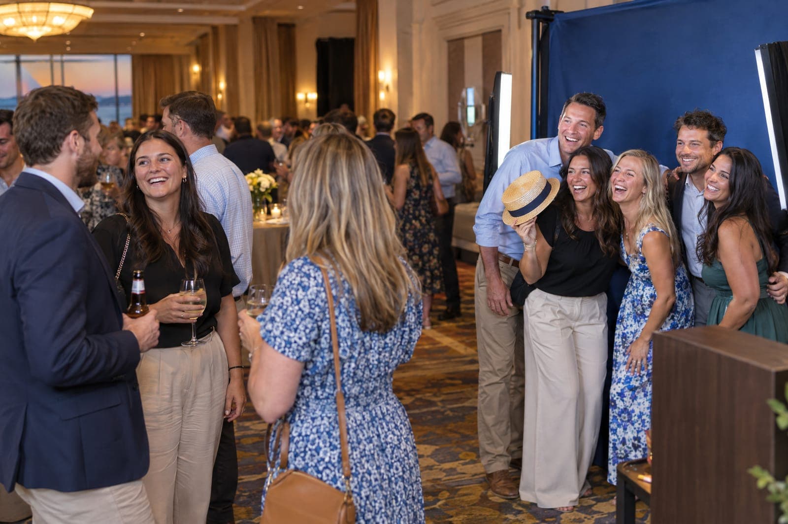 Example scene: coworkers at a hotel ballroom party crowding a photo booth with a blue backdrop